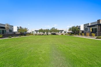 A large green lawn in front of some apartments